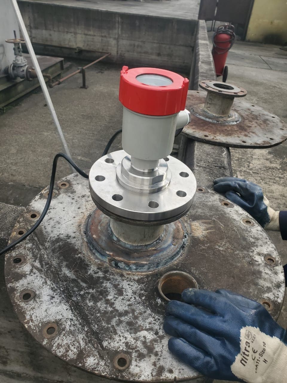 An 80 GHz radar level sensor installed on the manway flange of a diesel storage tank
